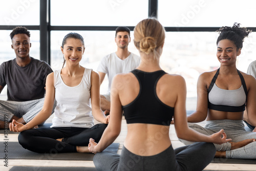 Group of multicultural man and woman practicing yoga with instructor in studio