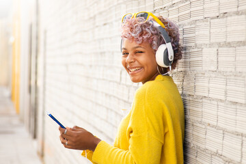 Wall Mural - girl with mobile phone and headphones on the city street