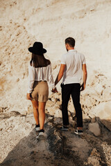 Wall Mural - Loving pair walking on a rocky mountain, enjoying beautiful mountain landscape. They holding hands.