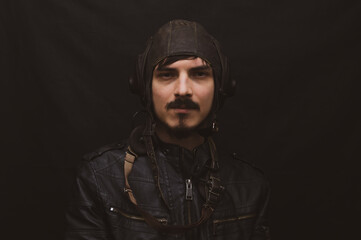 Male portrait in retro style. young man in the vintage aviation costume on the black background