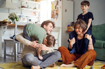 Modern caucasian happy family have fun and speding time with sons at home, parents playing with kids