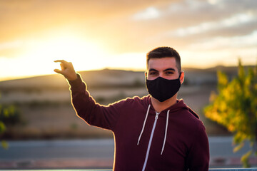 Wall Mural - Chico joven con mascarilla negra al atardecer