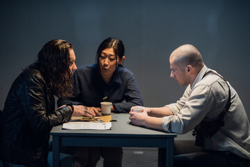 At the police station, two officers are interrogating the captured criminal.