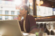 © Tom Merton/Caia Image - Serious businesswoman with laptop working in sunny restaurant