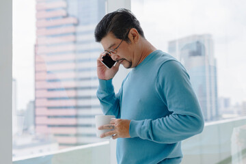 Wall Mural - Senior man in blue long sleeve shirt wearing eyeglasses talking on the phone.