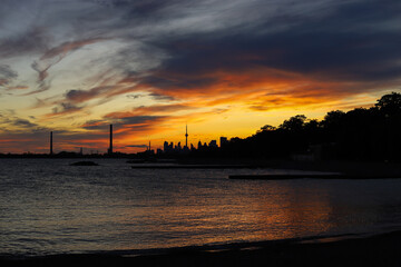 Wall Mural - Sunset in city Toronto. Darkness cityscape and golden hour.  Blue and yellow colors cloudy sky and lake Ontario