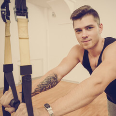 Wall Mural - Portrait of handsome young athlete doing suspension training with fitness straps