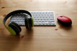 White keyboard with wireless mouse and bluetooth wireless headphones on wooden background.Top view. Computer equipment accessories