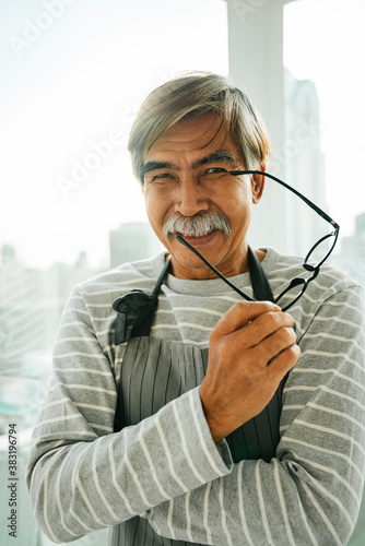 Old elderly senior waiter with eyeglasses in restaurant.