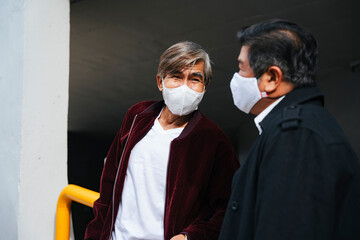 Wall Mural - Elderly senior people wearing mask talking about business outdoors in city.