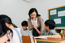 Young Asian Teacher Giving Boy High Five In School, Success, Achievement, Happiness. Asia School Boy With Young Woman In Class.