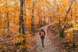 Woman walking in autumn foliage forest woods in city park with backpack. Travel hike fall destination in Quebec, Canada.