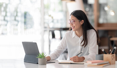 Young woman smiling while working with tablet at office, successful business concept.