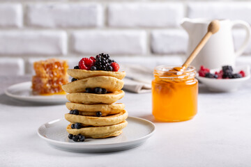 Wall Mural - Pancakes with fresh berries and honey on white table. Copy space.