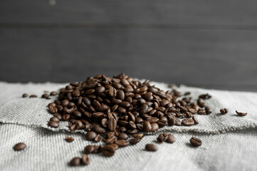 Coffee beans on a linen textile and on a wooden table background. Fresh arabica coffee beans.