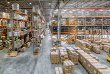 Large Industrial Warehouse. Tall Racks Are Completely Filled With Boxes And Containers.