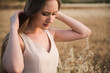 Beautiful young caucasian woman with long blond hair touching her hair on a background of a wheat field. selective focus portrait girl pensive