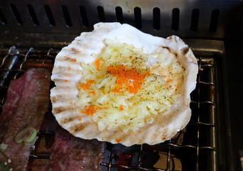 Focus on grilled scallops with cheese and fish roe melted on edges of oyster