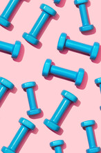 Fitness Dumbbells Blue On A Pink Background Pattern. Equipment For Home Workouts And Exercises In The Flat Lay Gym. Sports Dumbbell For A Healthy Lifestyle Top View.