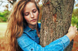 © iuricazac - Pretty young woman wearing a blue denim shirt hugging a big tree in the park posing on nature background.