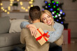 © Prostock-studio - Delighted wife holding xmas gift and hugging her husband