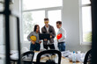 © speed300 - A team of professional young architects work in an office, one of them holding a laptop