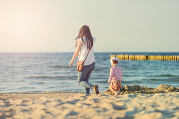 Happy mother and daughter in the park. Beauty nature scene with family outdoor lifestyle. Happy family resting together on the green grass, having fun outdoor. Happiness and harmony in family life