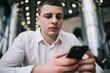 © BullRun - Serious man with wireless earbuds using smartphone in modern cafe