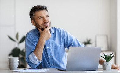 Wall Mural - Handsome Male Entrepreneur Sitting At Workplace With Thoughtful Face Expression