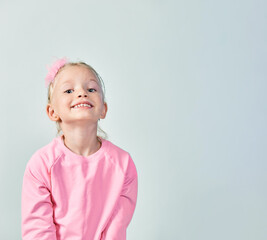 Cute girl 4-5 year old posing in studio in a pink sweatshirt