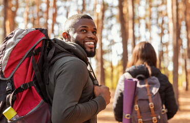 happy black guy looking aside, hiking with girlfriend