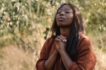 Afro Girl closed her eyes, praying. Hands folded in prayer concept for faith, spirituality and religion