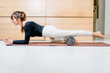 © Iryna - Seria photo of sports woman using foam roller for exercise at home. Method to release tension and help with muscle pain, a tool for exercise, physical therapy and training.