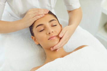 Wall Mural - Close-up of serene woman getting procedure of relaxing manual facial massage from masseur