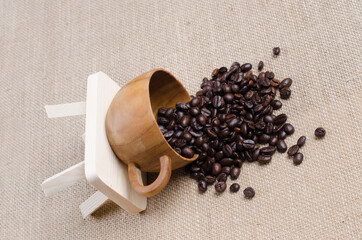 Wall Mural - The coffee beans spill in the coffee wooden cup on the hessian sack  for background , texture , copy text, Love coffee concept