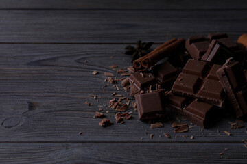 Delicious milk chocolate and cinnamon on wooden table. Space for text