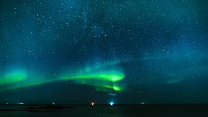 amazing northern lights dancing above the sea in northern norway, stars moving behind the aurora bor