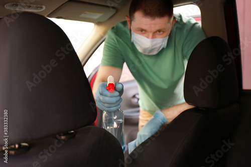 Man cleaning car salon with disinfectant spray