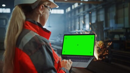 Poster - Professional Heavy Industry Engineer Uses Laptop Computer with Green Screen Mock Up Display. Female Industrial Specialist Working in a Metal Manufacture Warehouse with Sparks in the Background.