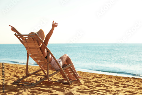 Cuadros en Lienzo Woman relaxing on deck chair at sandy beach. Summer vacation