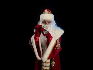 Santa Claus in a red fur coat, with a white beard posing on a black background