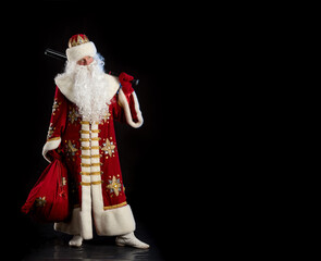 Santa Claus in a red fur coat, with a white beard posing on a black background