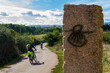 © Csar - Pilgrims cyclists on the route of the Camino de Santiago (Way of Saint James) passing next to the scallop shell that marks the way