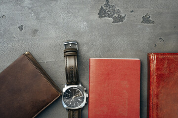 Businessman's accessories including notepad, watch and purse on dark grey background