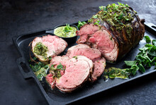 Traditional English Barbecue Lamb Roast Sliced With Mint Leaf And Sauce Offered As Close-up In A Design Cast-iron Tray