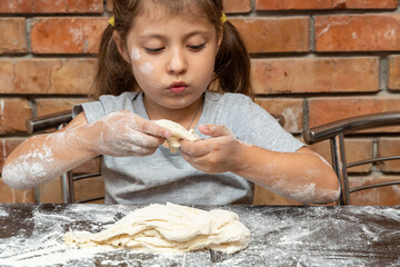 cute little girl kneading dough, preparing dough for baking