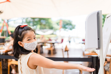 Wall Mural - Coronavirus Covid-19 concept.Little asian chinese girl wearing mask for protect coronavirus and clean hand with alcohol gel sanitizer auto pump before come to restaurant for stop coronavirus.Hygiene.