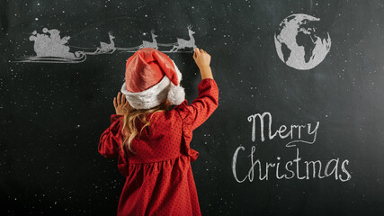 a Girl in santa claus hat draws christmas drawing on the blackboard