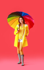 Wall Mural - Beautiful young woman in raincoat and with umbrella on color background