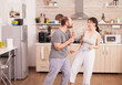 © DC Studio - Carefree happy and joyful couple dancing and singing in kitchen in synny morning. Cheerful husband and wife laughing, singing, dancing listening musing, living happy and worry free. Positive people